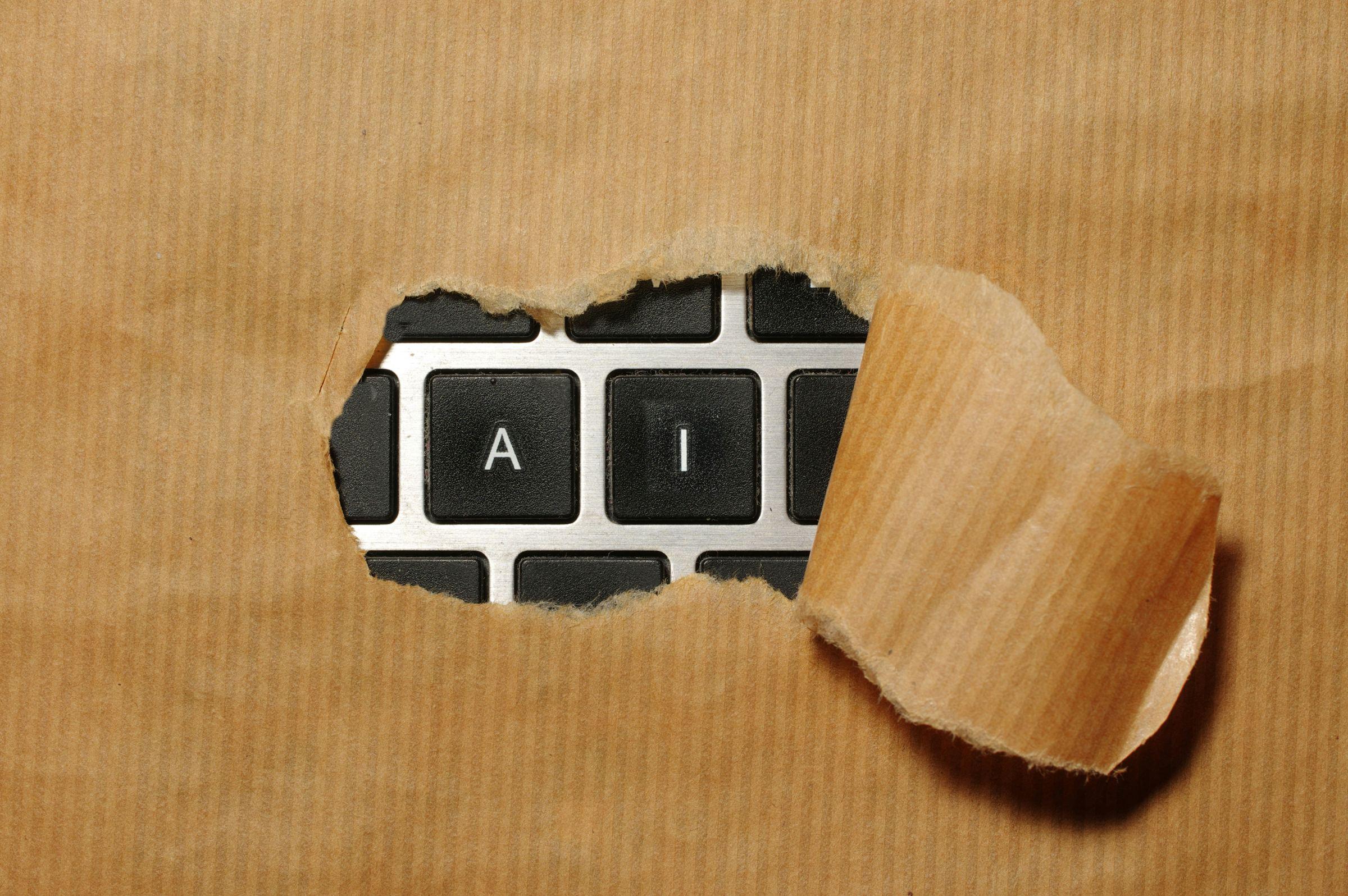 Pocepan smeđi pakpapir kroz čiji otvor se vide crni tasteri tastature sa slovima A i I